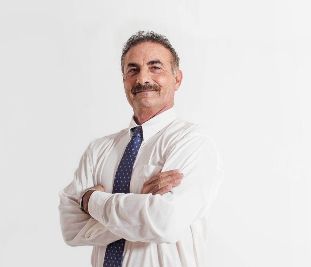 A man with his arms crossed wearing a white shirt and tie.
