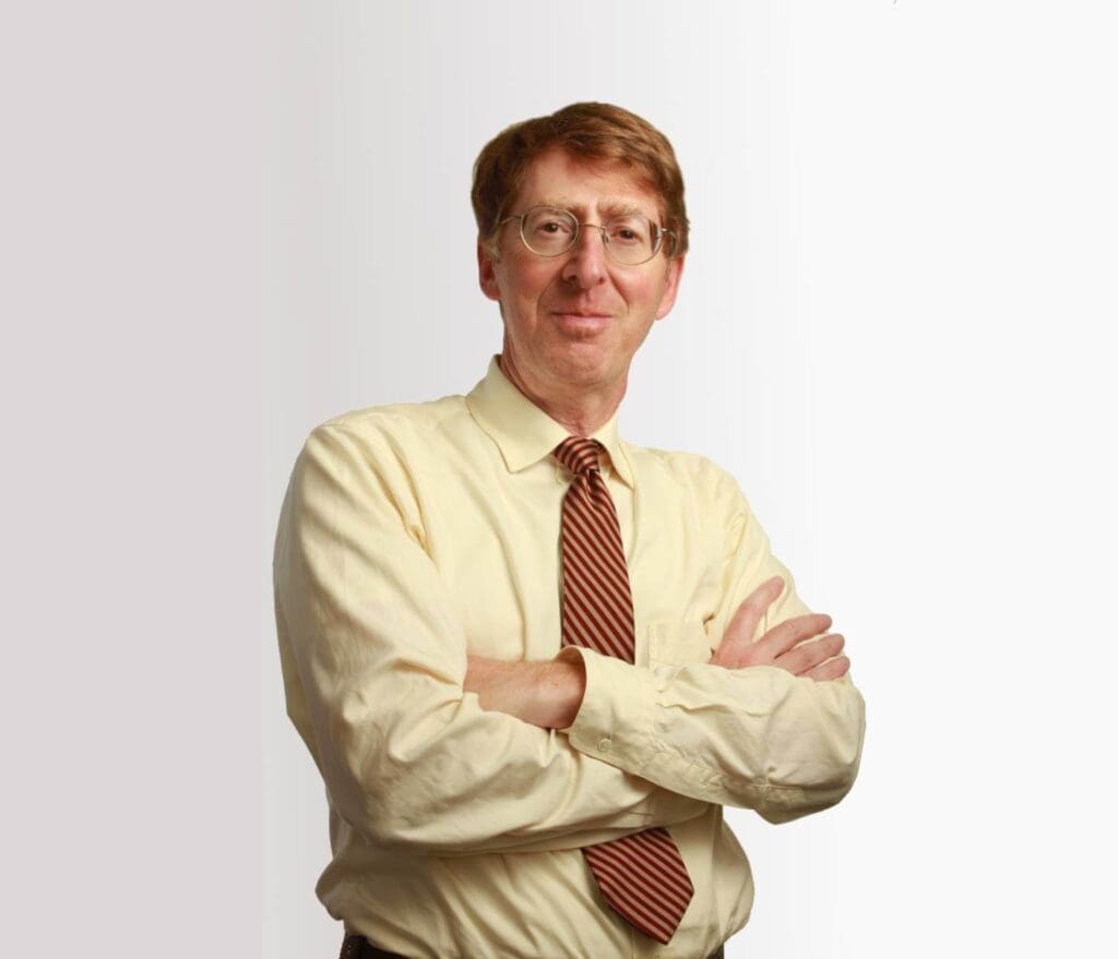 A man with his arms crossed wearing glasses and a tie.