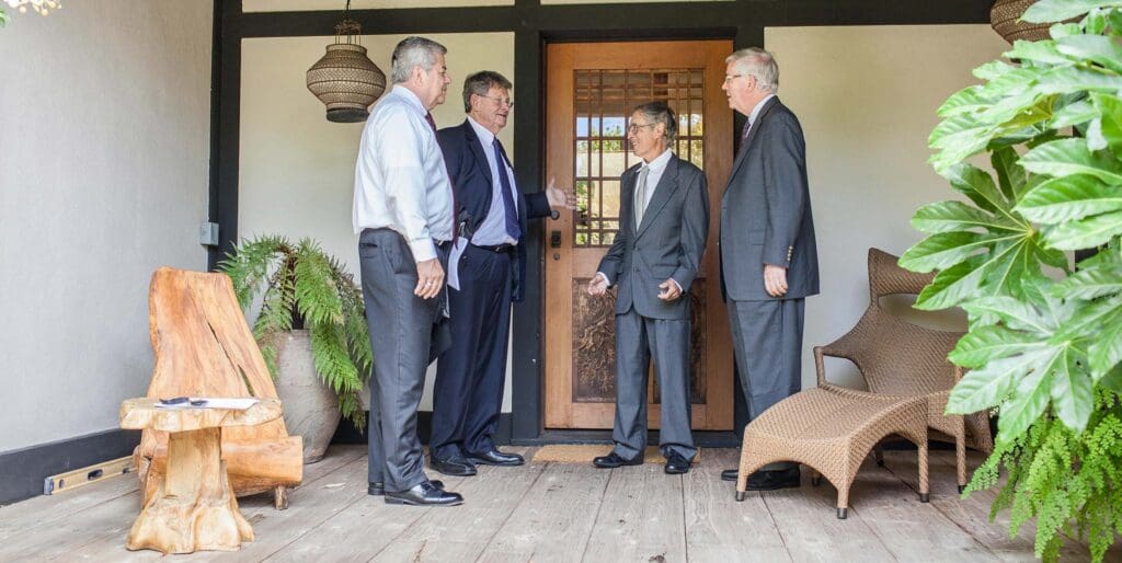 Four men in suits standing outside of a house.